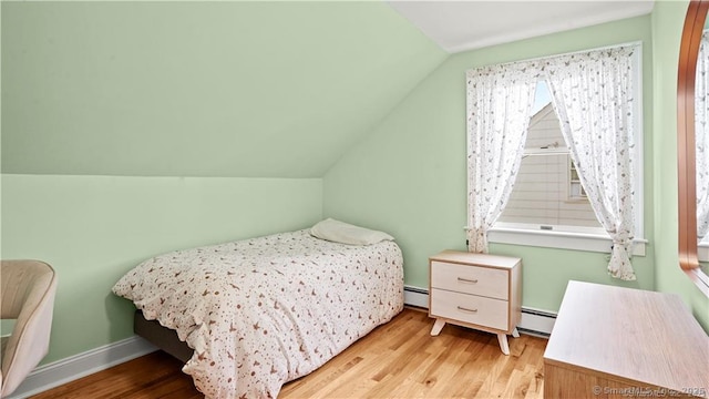 bedroom featuring baseboards, vaulted ceiling, baseboard heating, and wood finished floors