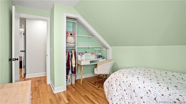 bedroom featuring vaulted ceiling, a closet, wood finished floors, and baseboards