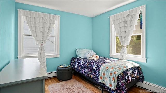 bedroom with baseboard heating and wood finished floors