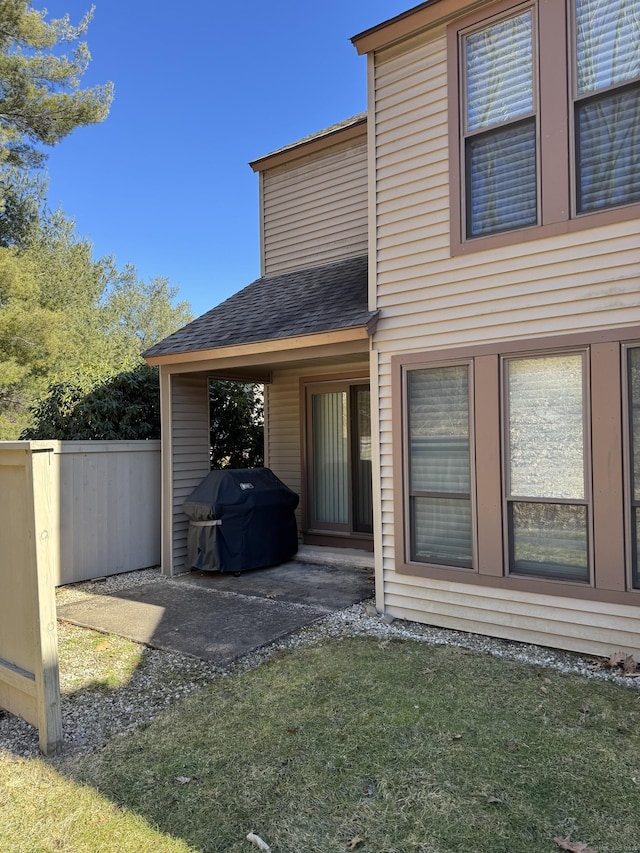 rear view of house with a yard, fence, and roof with shingles