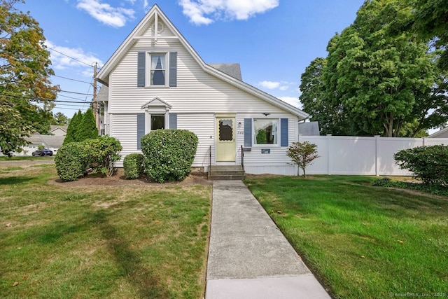 view of front of home with entry steps, a front lawn, and fence