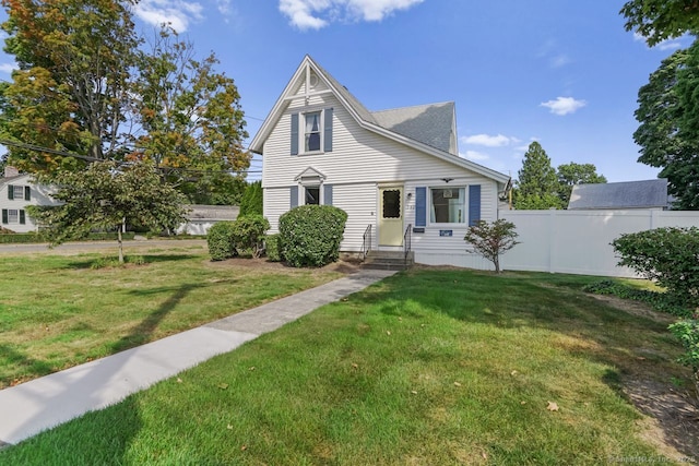 view of front facade with entry steps, fence, and a front lawn