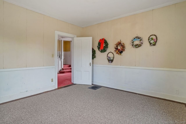 spare room with carpet flooring, crown molding, visible vents, and stairs