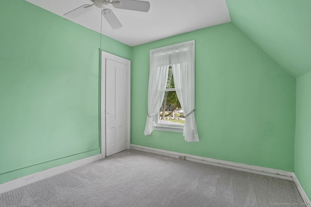 unfurnished bedroom featuring carpet, lofted ceiling, a closet, ceiling fan, and baseboards