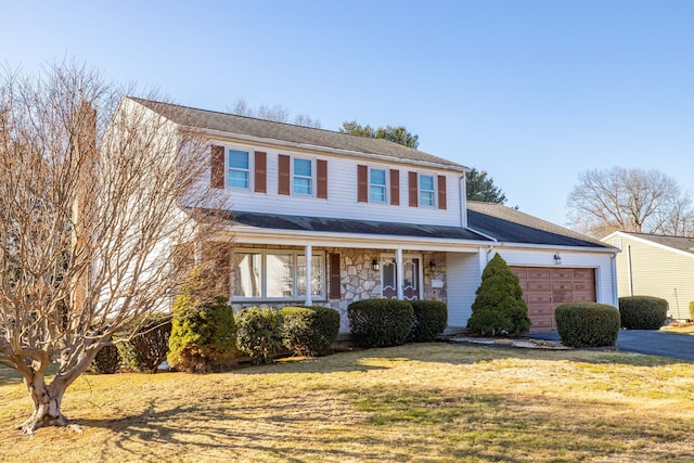 traditional-style house with a porch, stone siding, an attached garage, and a front lawn