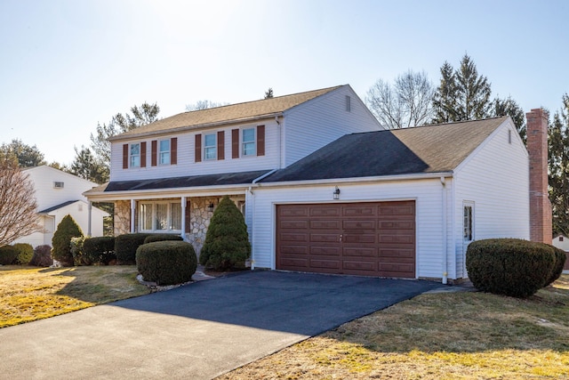 traditional-style home with aphalt driveway, a front yard, a chimney, stone siding, and an attached garage