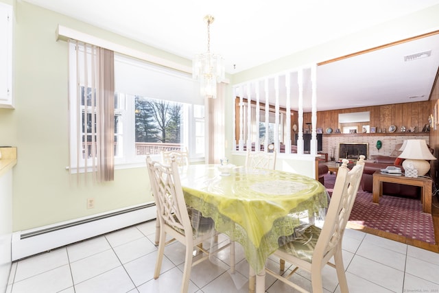 dining area featuring light tile patterned floors, a fireplace, an inviting chandelier, and a baseboard radiator