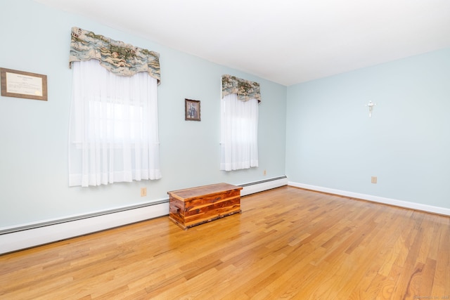 unfurnished room with a baseboard radiator, baseboard heating, a healthy amount of sunlight, and wood finished floors