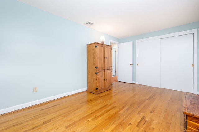 unfurnished bedroom featuring light wood-style flooring, baseboards, visible vents, and a closet