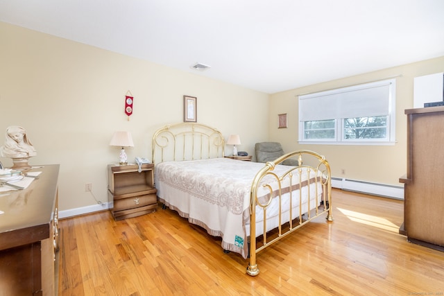 bedroom with light wood finished floors, visible vents, baseboards, and a baseboard radiator