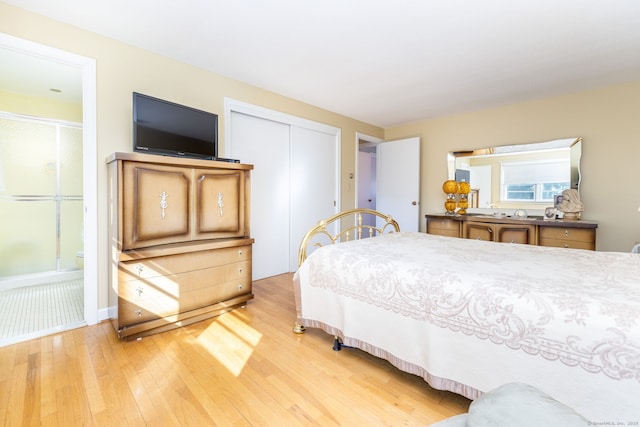 bedroom featuring light wood-type flooring, a closet, and ensuite bath