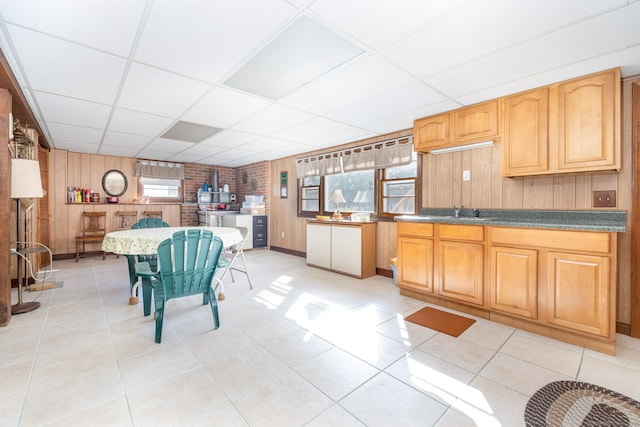 kitchen featuring wooden walls, light tile patterned floors, and a drop ceiling