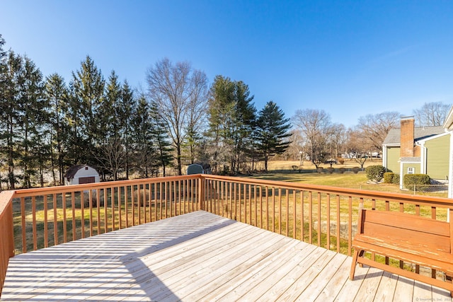 wooden terrace with a shed, a lawn, and an outdoor structure