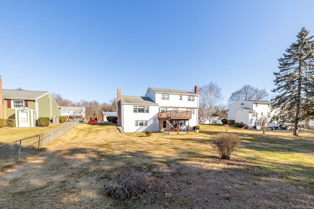 back of property with a lawn, a chimney, a deck, and fence