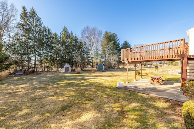 view of yard featuring a patio area, a shed, an outdoor structure, and a deck