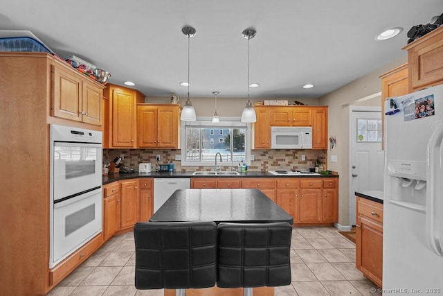 kitchen with a sink, white appliances, dark countertops, and light tile patterned floors