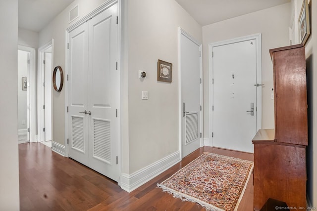 hall with wood finished floors, visible vents, and baseboards