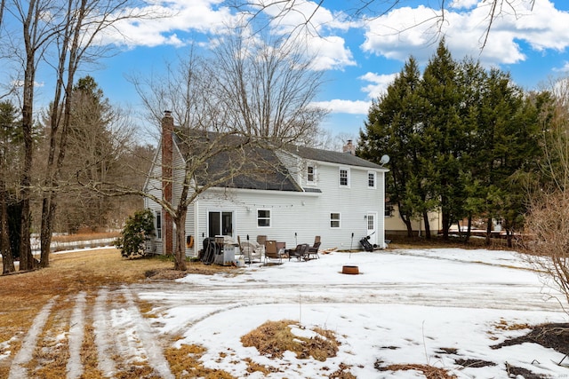 snow covered back of property with a chimney