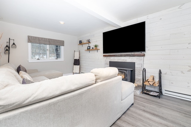 living room featuring a stone fireplace, beamed ceiling, wood walls, and light wood finished floors