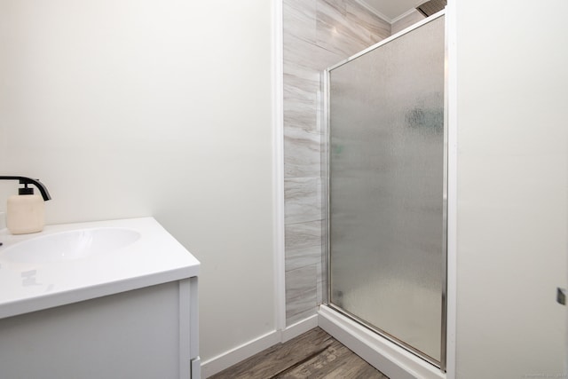 bathroom with a stall shower, a sink, baseboards, and wood finished floors