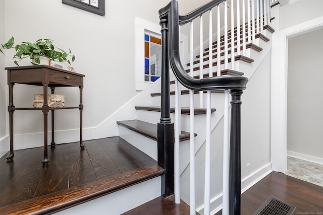 stairs featuring wood finished floors, visible vents, and baseboards