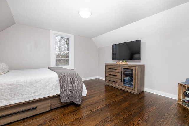 bedroom with baseboards, vaulted ceiling, and wood finished floors