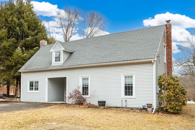 back of house with a shingled roof and a chimney