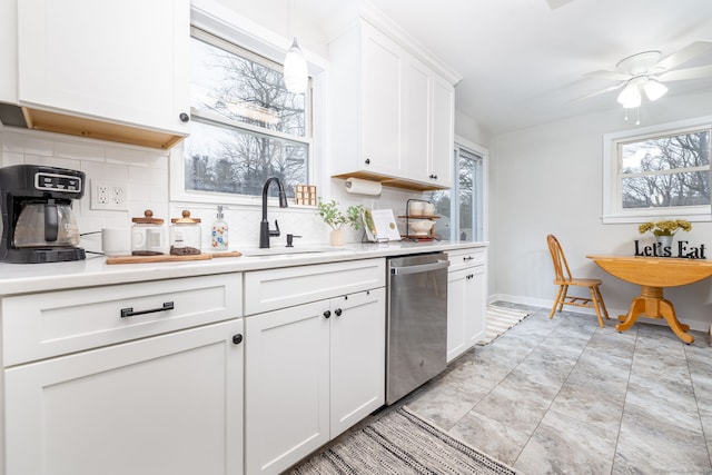 kitchen with tasteful backsplash, light countertops, stainless steel dishwasher, white cabinetry, and a sink