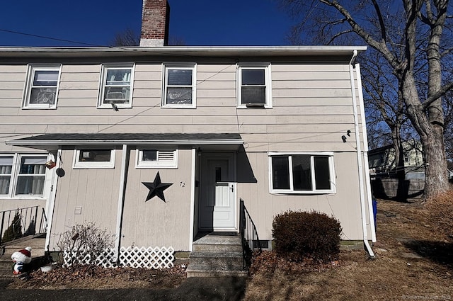 view of front of home with entry steps and a chimney