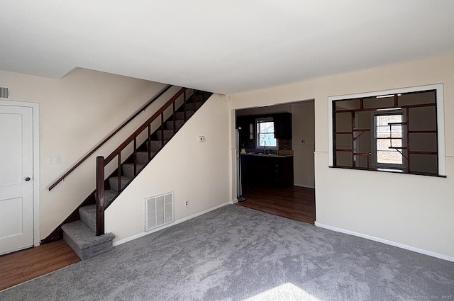 interior space with a sink, visible vents, baseboards, stairs, and carpet