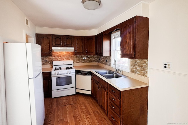 kitchen featuring dark wood-style floors, visible vents, a sink, white appliances, and under cabinet range hood