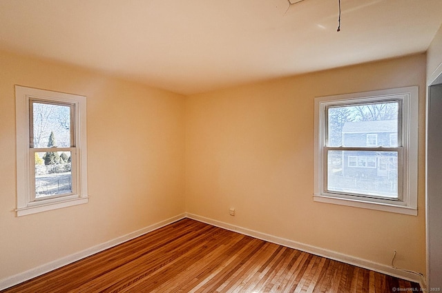 unfurnished room featuring baseboards, a wealth of natural light, and wood finished floors