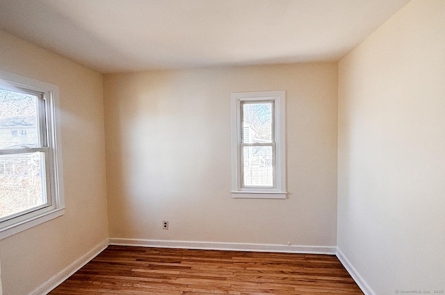 unfurnished room featuring plenty of natural light, wood finished floors, and baseboards