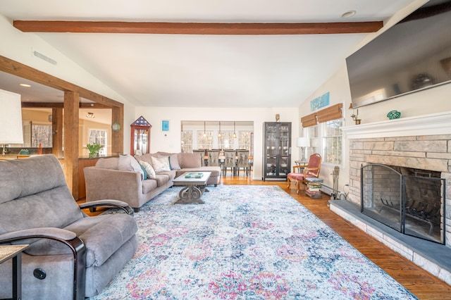 living area featuring visible vents, a fireplace, lofted ceiling with beams, and wood finished floors