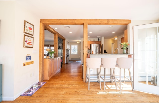 kitchen with a breakfast bar, light wood-style flooring, freestanding refrigerator, recessed lighting, and baseboards