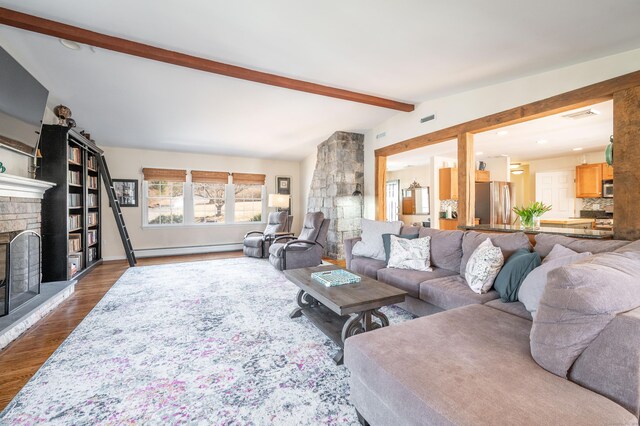 living area with dark wood-style floors, visible vents, lofted ceiling with beams, a stone fireplace, and a baseboard heating unit