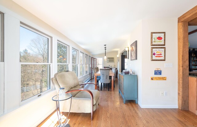 interior space featuring baseboards, lofted ceiling, wood finished floors, and a wall unit AC