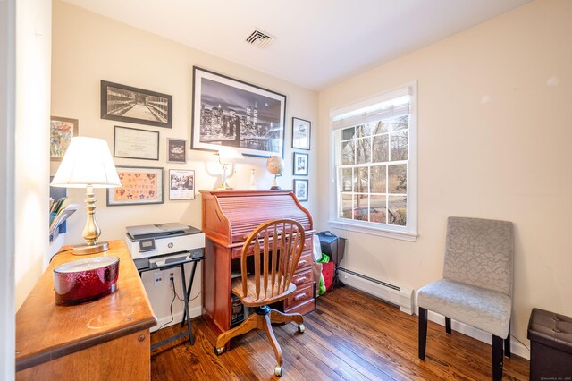 office space featuring a baseboard heating unit, wood finished floors, visible vents, and baseboards