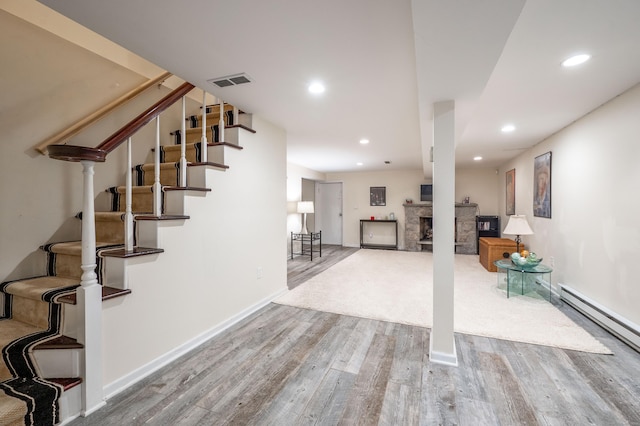 staircase with a baseboard heating unit, recessed lighting, wood finished floors, and visible vents