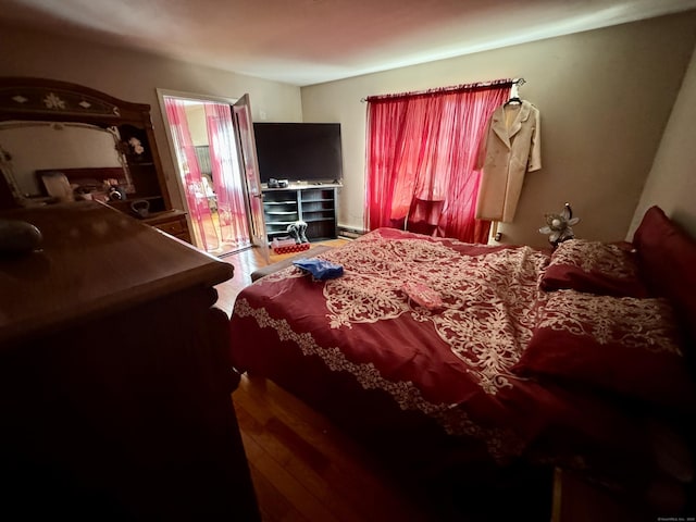 bedroom featuring a baseboard heating unit and wood finished floors