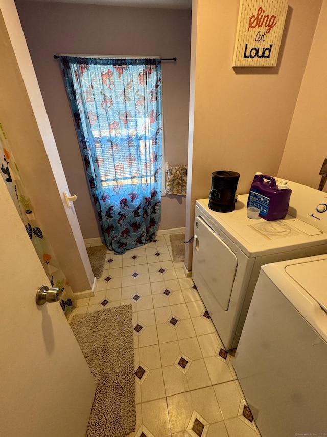 washroom featuring laundry area, baseboards, and washing machine and clothes dryer