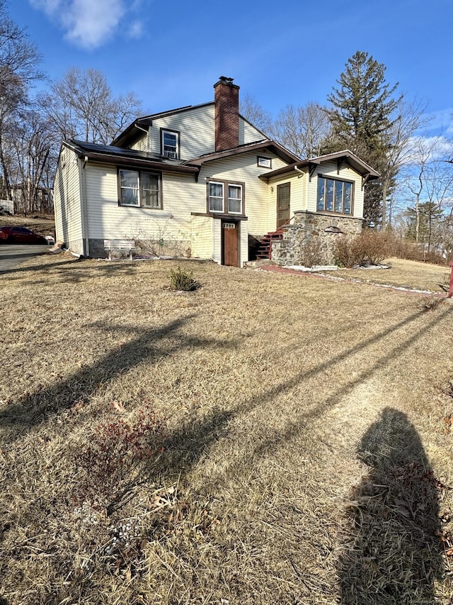 exterior space featuring brick siding, a chimney, and a front lawn