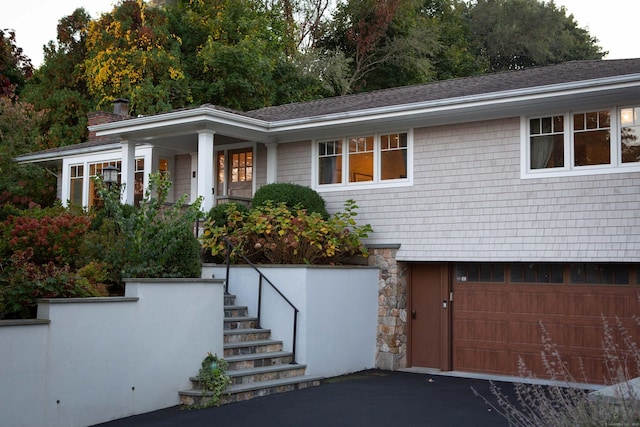 9 Schiller Rd, Fairfield, CT 06825 - view of front of property featuring stairway, driveway, a shingled roof, a garage, and stone siding