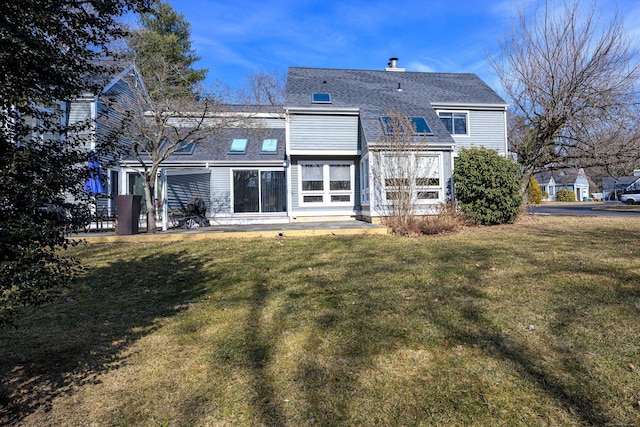 back of house with a patio area, a shingled roof, a chimney, and a yard