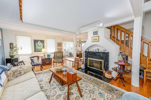 living room featuring visible vents, a fireplace, a notable chandelier, and wood finished floors