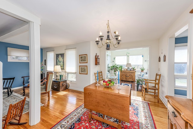 dining room featuring a chandelier, baseboards, and light wood finished floors