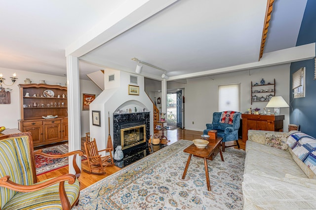 living area featuring baseboards, visible vents, wood finished floors, rail lighting, and a fireplace