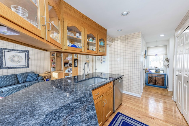 kitchen with dishwasher, light wood-type flooring, a sink, and glass insert cabinets