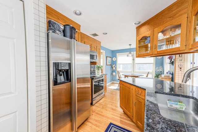 kitchen featuring stainless steel appliances, glass insert cabinets, and brown cabinets