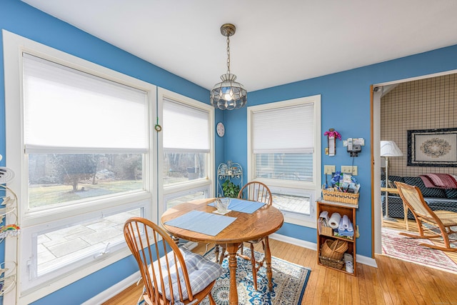 dining room with light wood-type flooring, a notable chandelier, and baseboards